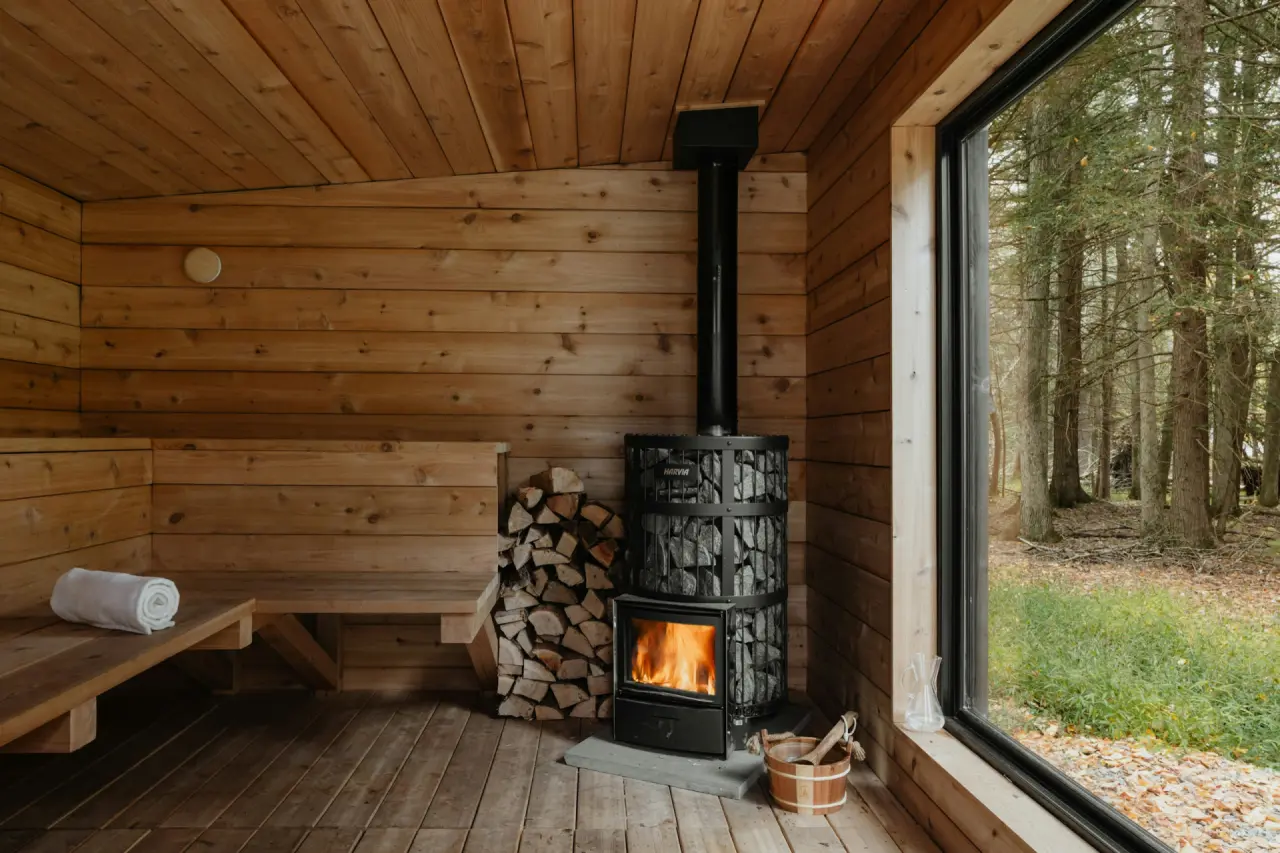 Holzsauna mit Kaminofen und großem Fenster zum Wald