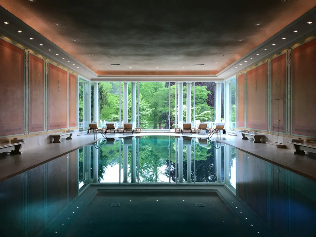 Hallenbad eines Hotels mit großer Fensterfront zum Garten