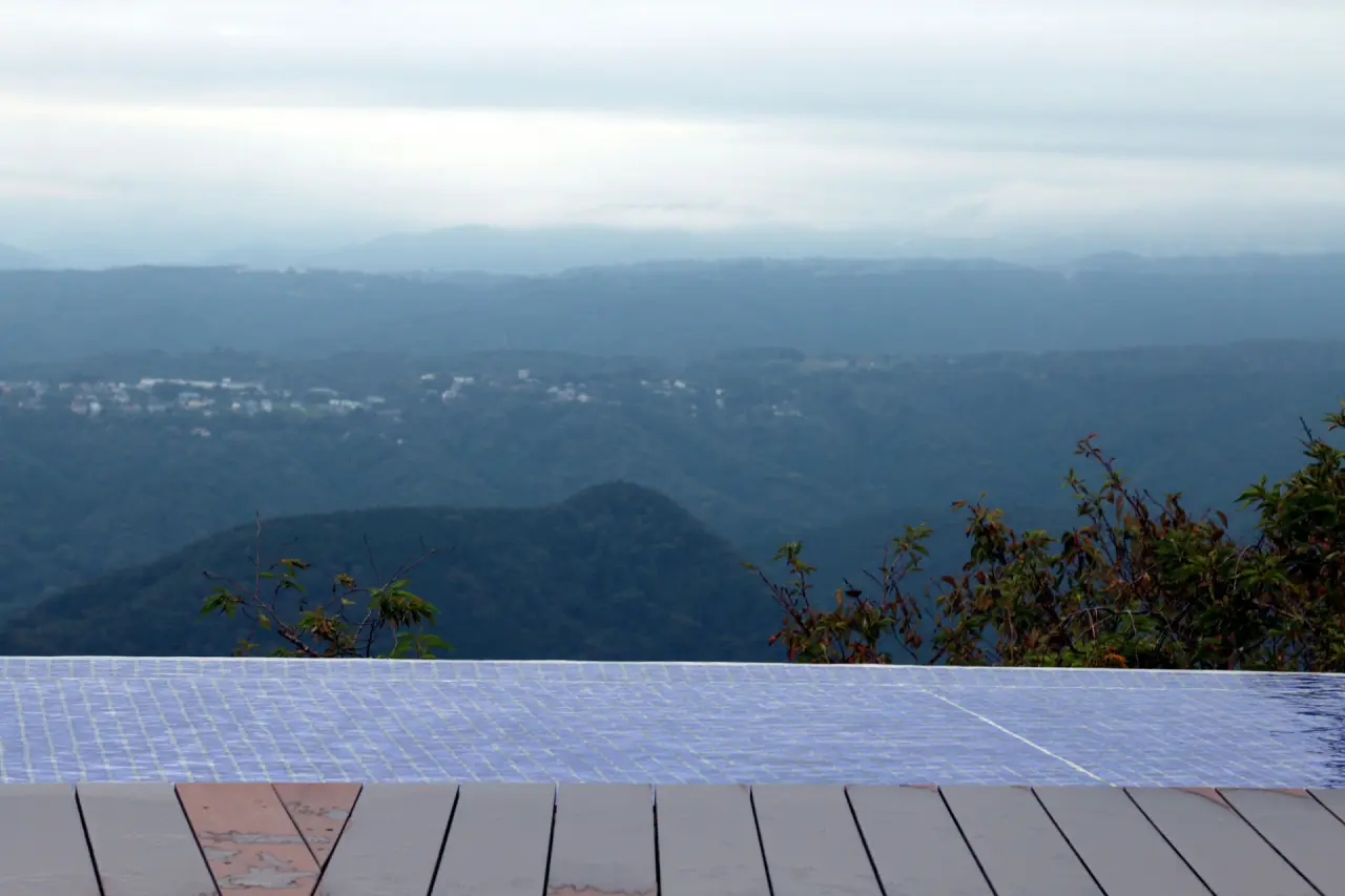 Infinity-Pool mit Holzdeck vor weitem Bergpanorama