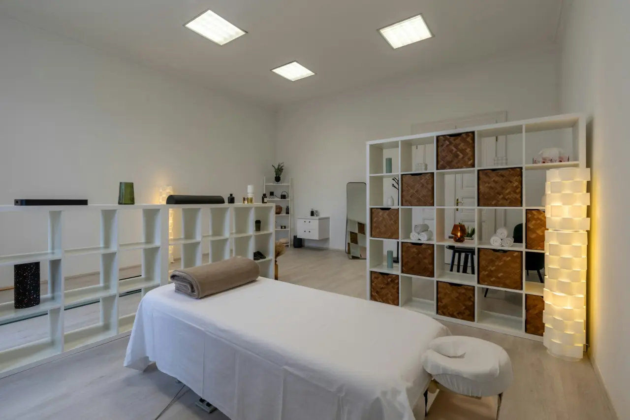 Behandlungsraum mit Liege und Regalen in hellem Licht