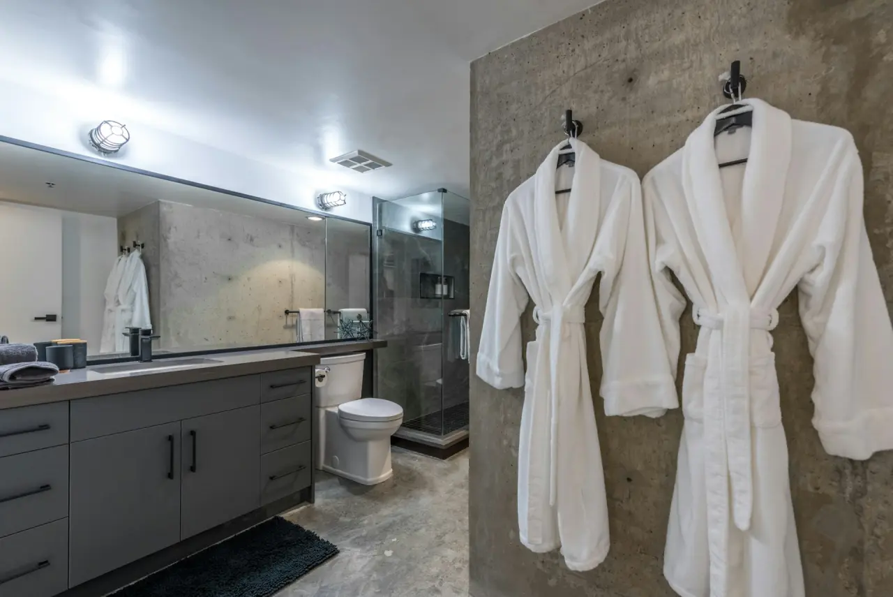 Zwei weiße Bademäntel an Haken im Hotelbad