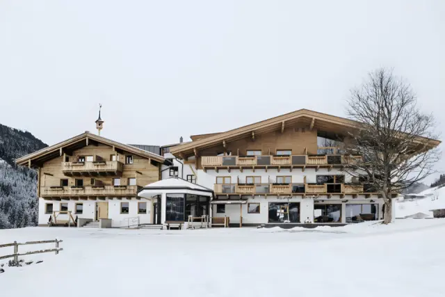 Thurnerhof in Saalbach – Traditionelles Hotelgebäude im Winter mit verschneiter Landschaft | Wellnesshotel Salzburger Land