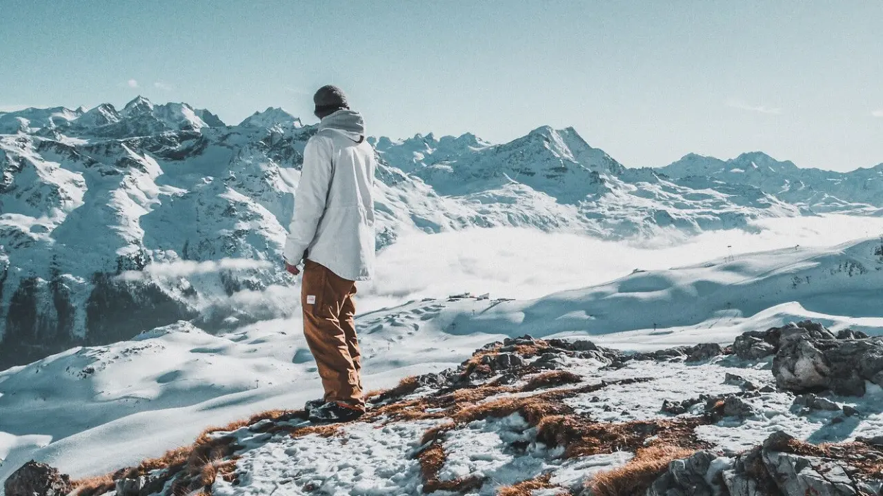 Carlton Hotel in St. Moritz – Wanderer genießt den Panoramablick auf die verschneiten Alpen | Wellnesshotel Engadin