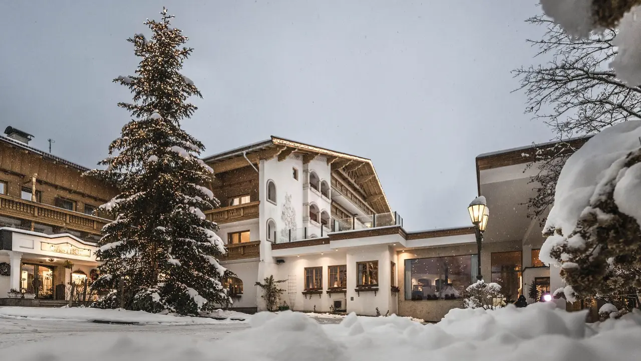 Wohlfühlresort Peternhof in Kössen – Festlich beleuchtete Hotelfassade im Schnee mit Weihnachtsbaum | Wellnesshotel Tirol