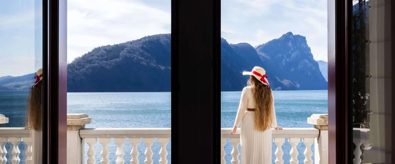 Hotel Vitznauerhof in Vitznau – Frau genießt den Ausblick vom Balkon auf den Vierwaldstättersee | Wellnesshotel Vierwaldstättersee