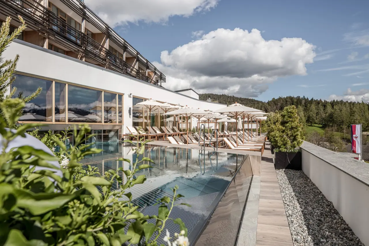 Hotel Nidum in Mösern – Außenpool mit Liegen und Sonnenschirmen an einem sonnigen Tag | Wellnesshotel Tirol