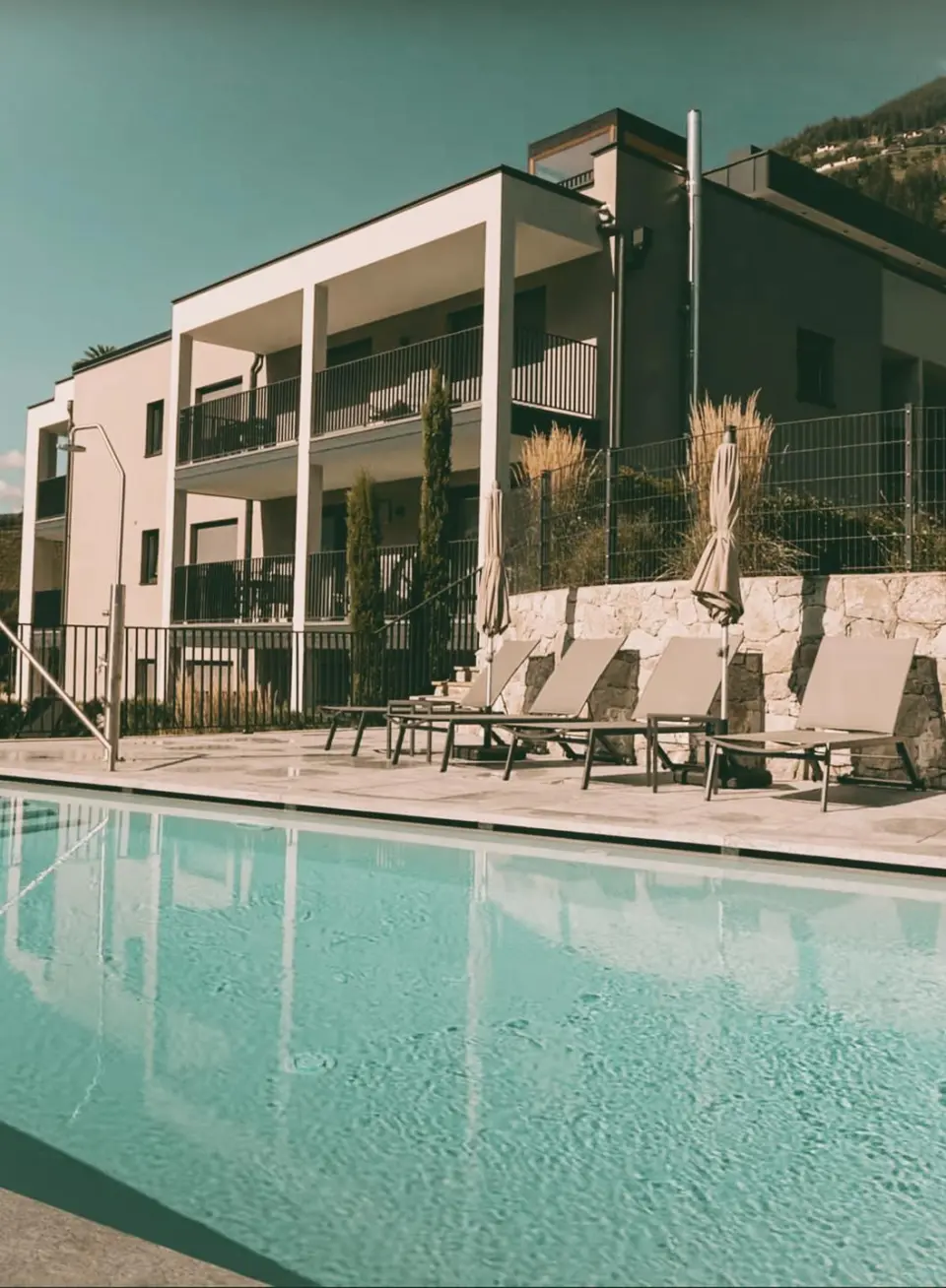 Hotel Saltauserhof in Saltaus – Moderner Außenpool mit Liegebereich und Hotelgebäude | Wellnesshotel Südtirol