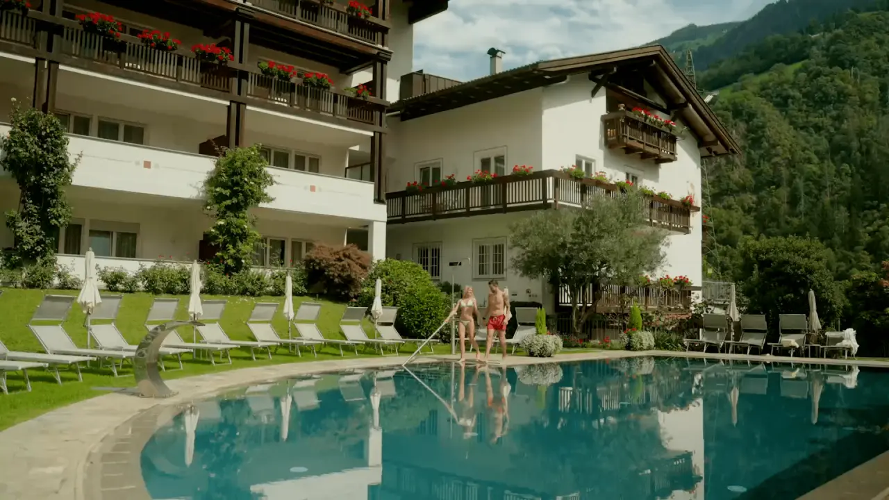 Hotel Saltauserhof in Saltaus – Außenpool mit Liegewiese und Hotelgebäude | Wellnesshotel Südtirol