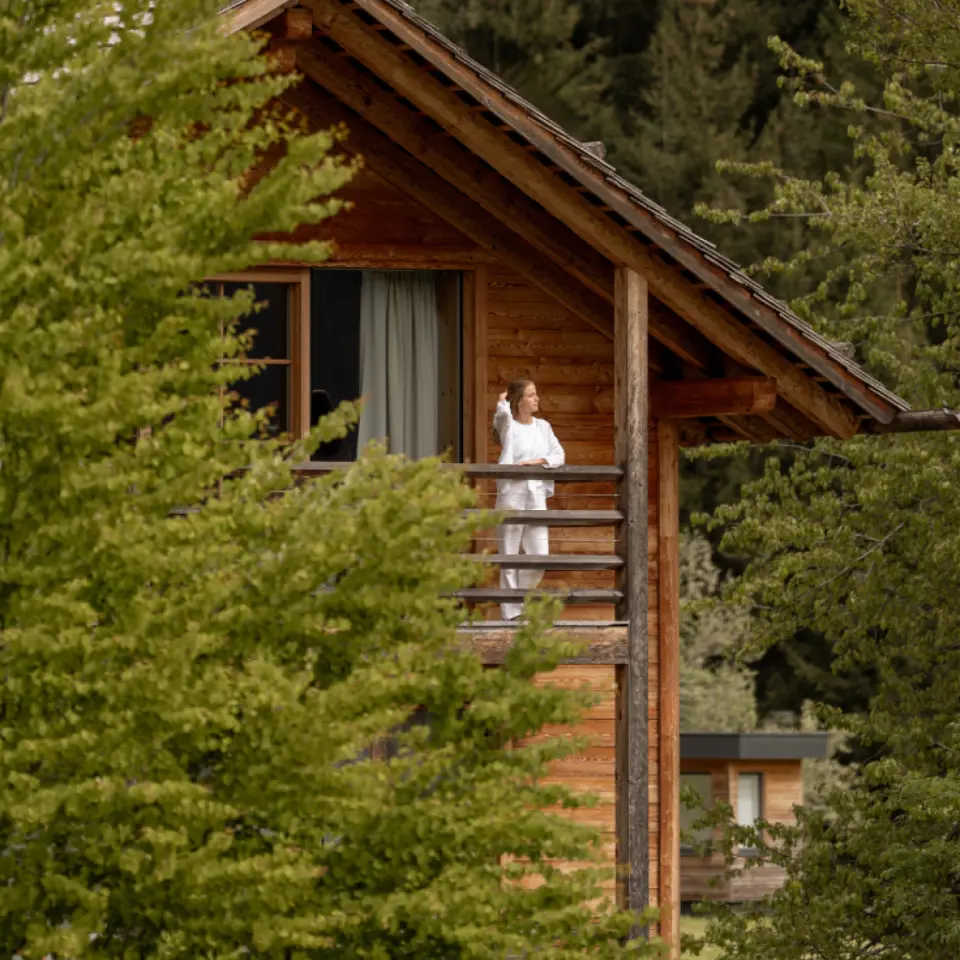 Naturhotel Lüsnerhof in Ehrenburg – Frau auf dem Balkon eines Holzchalets | Wellnesshotel Südtirol