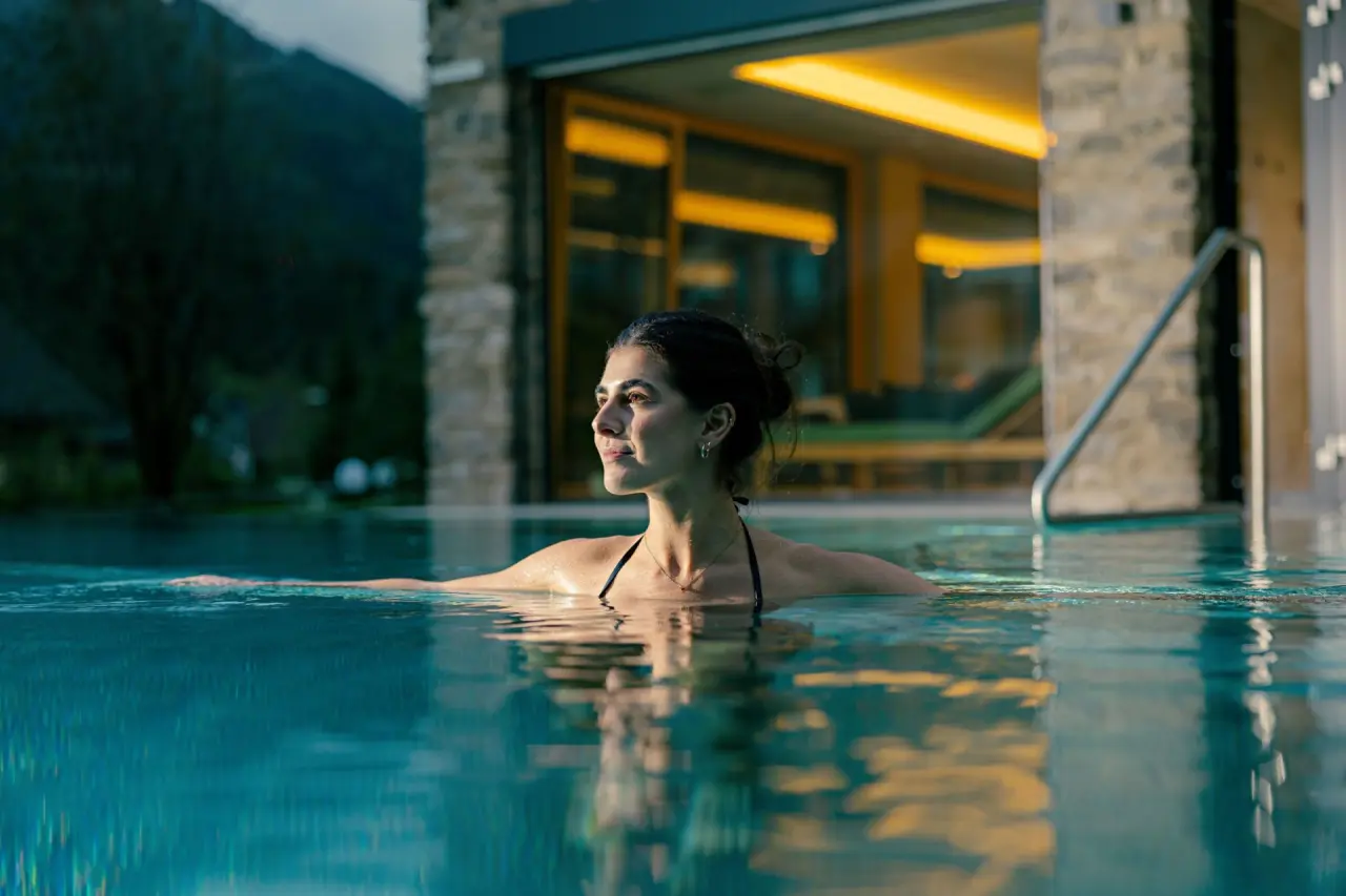 Evident Hotel Prägant in Bad Kleinkirchheim – Frau entspannt im beleuchteten Außenpool | Wellnesshotel Kärnten
