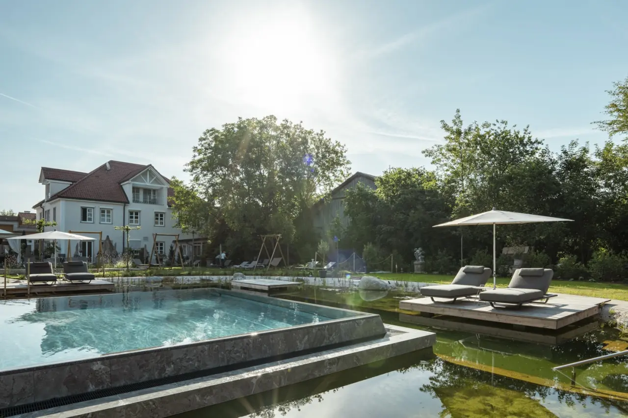 Das Mühlbach Thermal Spa in Bad Füssing – Außenpool mit Liegewiese und Hotelgebäude | Wellnesshotel Niederbayern