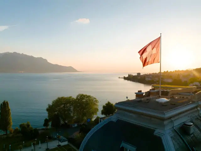 Fairmont - Montreux Palace in Montreux – Sonnenuntergang über dem Genfersee mit Hotel und Bergen | Wellnesshotel Genfersee