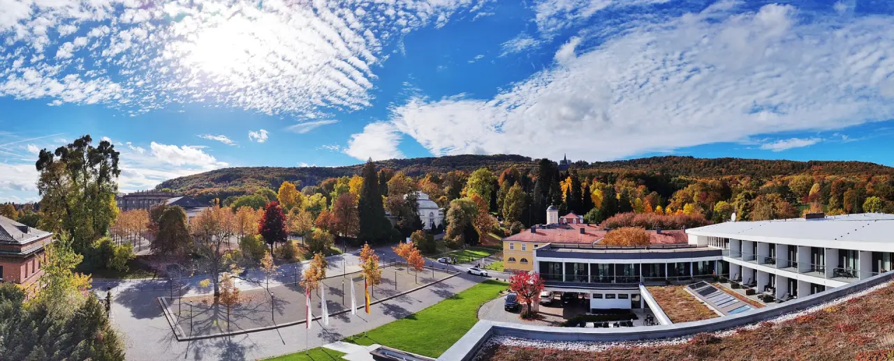 Schlosshotel Bad Wilhelmshöhe in Kassel – Panorama-Außenansicht im Herbst mit Wald und blauer Himmel | Wellnesshotel Hessen