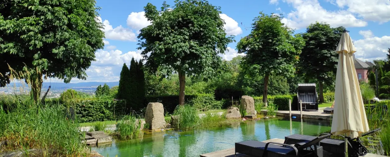 Schlosshotel Bad Wilhelmshöhe in Kassel – Naturbadeteich mit Liegen und grüner Umgebung im Sommer | Wellnesshotel Hessen
