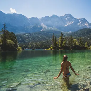Hotel Zugspitze in Garmisch-Partenkirchen – Frau im klaren Bergsee mit Alpenpanorama | Wellnesshotel Alpen