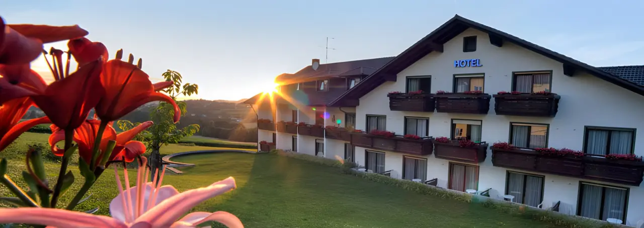 Urlaubshotel Binder in Büchlberg – Hotelaußenansicht bei Sonnenuntergang mit Blumen | Wellnesshotel Bayerischer Wald