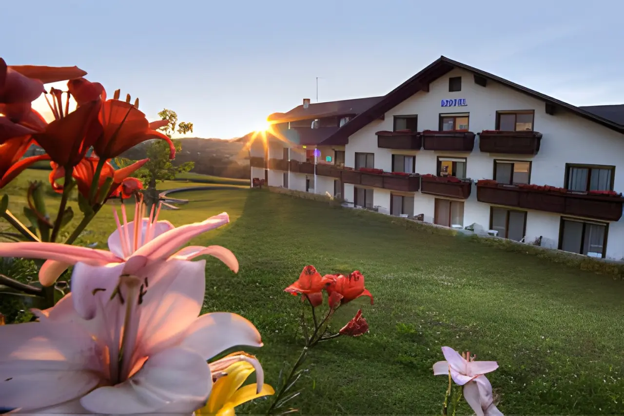 Urlaubshotel Binder in Büchlberg – Hotelgebäude im Abendlicht mit blühenden Blumen | Wellnesshotel Bayerischer Wald
