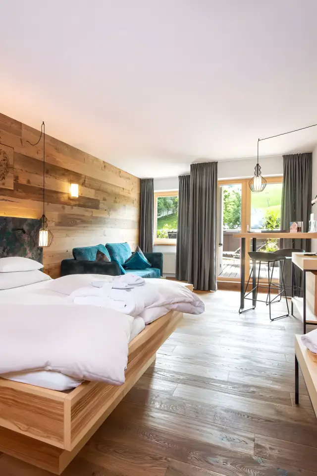 LEBE FREI Hotel DER LÖWE in Leogang – Modernes Hotelzimmer mit Holzwand und Balkon | Wellnesshotel Salzburger Land