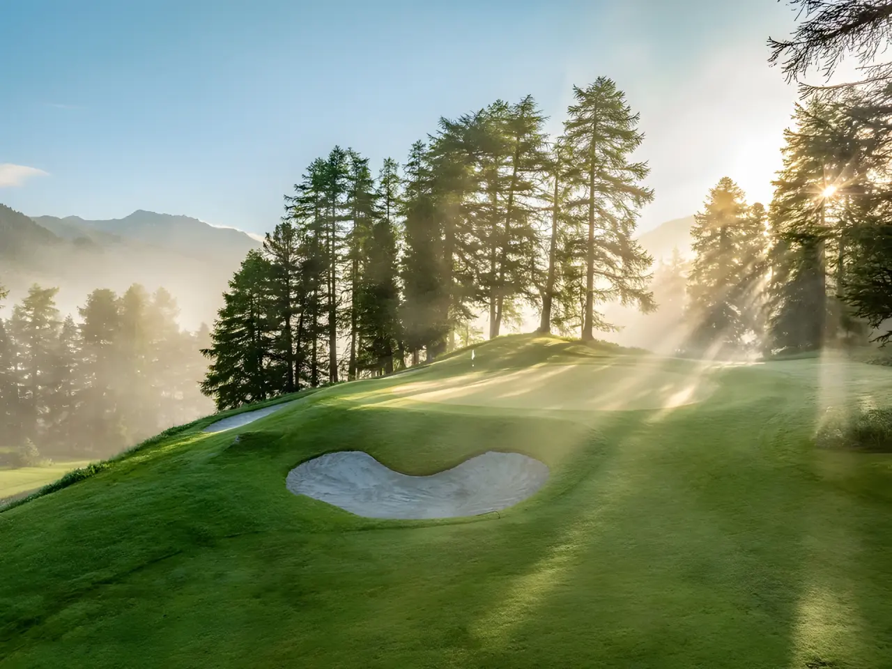 Kulm Hotel St. Moritz in St. Moritz – Golfplatz im Morgenlicht mit Bäumen | Wellnesshotel Engadin
