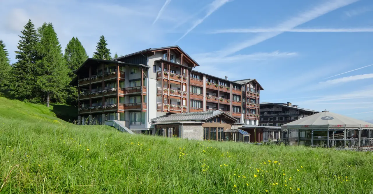 Hotel & Spa Wulfenia in Hermagor – Hotelgebäude im Sommer mit grünen Wiesen | Wellnesshotel Kärnten