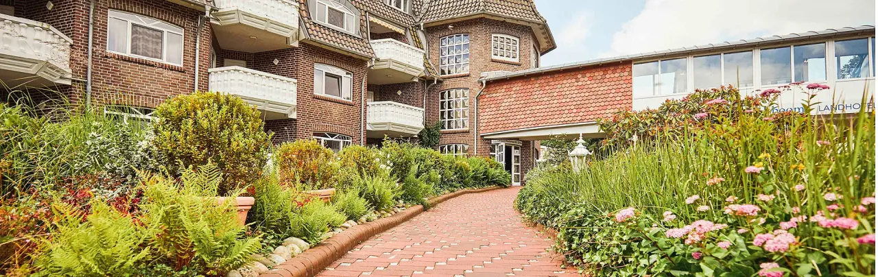 Upstalsboom Landhotel Friesland in Varel – Hotelgebäude mit grünem Gartenweg | Wellnesshotel Nordsee