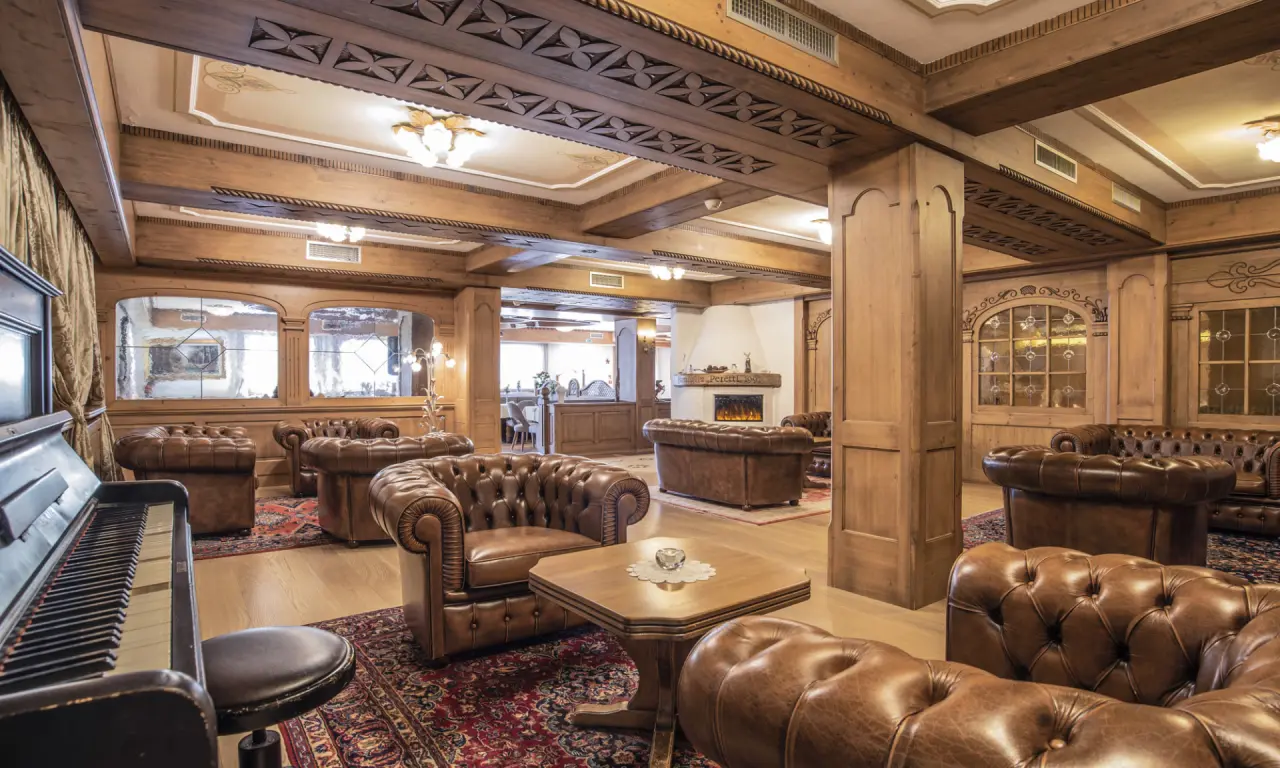 Rio Stava Family Resort & Spa in Tesero – Gemütliche Lobby mit Ledersesseln und Kamin | Wellnesshotel Trentino