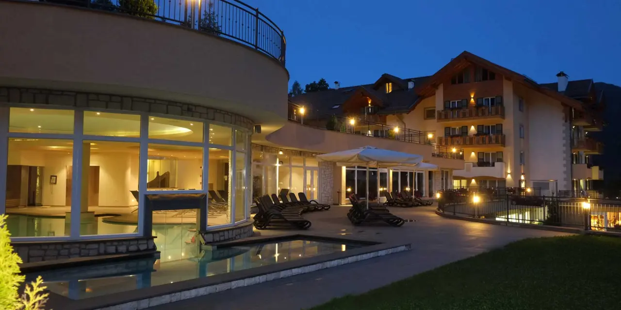 Rio Stava Family Resort & Spa in Tesero – Beleuchteter Außenpoolbereich am Abend | Wellnesshotel Trentino