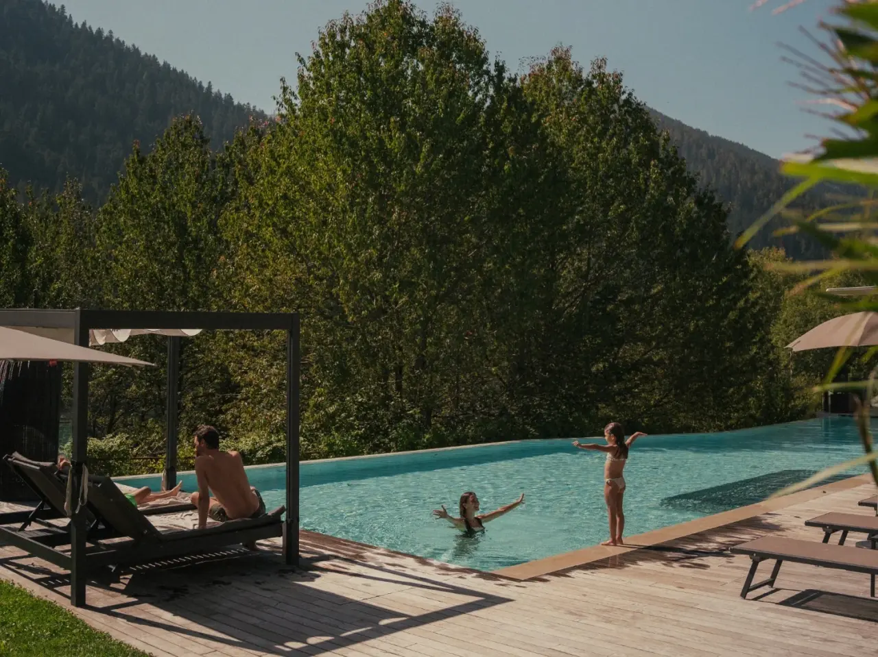engel gourmet&spa in Welschnofen – Sonniger Außenpoolbereich mit Gästen und Bergblick | Wellnesshotel Südtirol