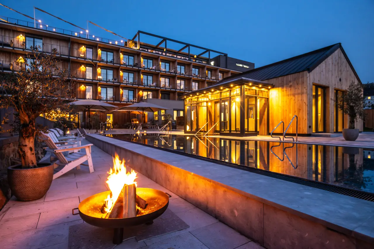 Papa Rhein Hotel in Bingen – Beleuchteter Außenpoolbereich bei Nacht mit Feuerstelle | Wellnesshotel Rheinhessen