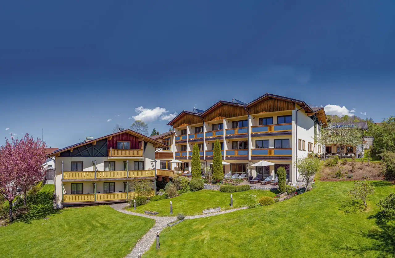 Glashotel Zwiesel in Zwiesel – Hotelaußenansicht im Frühling mit blühenden Bäumen | Wellnesshotel Bayerischer Wald