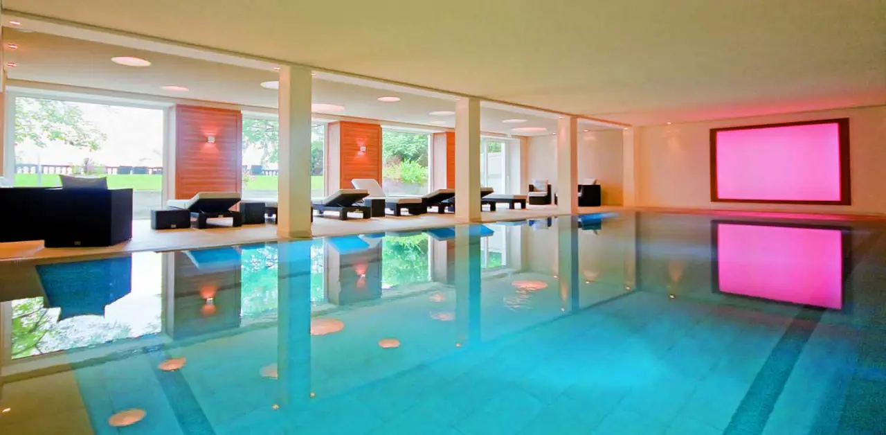 Hotel Bad Schachen in Lindau – Innenpool mit Ruheliegen und Blick ins Grüne | Wellnesshotel Bodensee