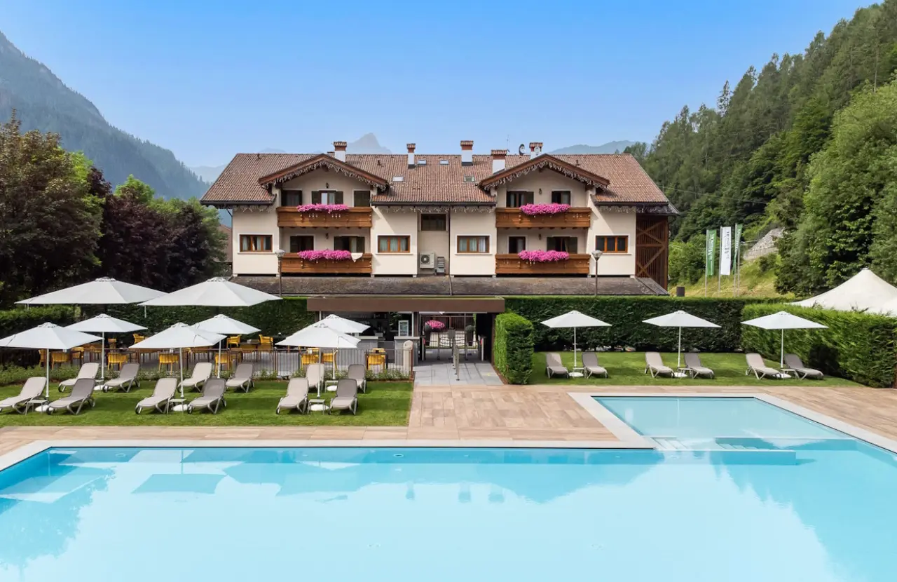 Hotel La Maison Wellness & Spa in Alleghe – Außenansicht mit großem Pool und Bergen | Wellnesshotel Dolomiten