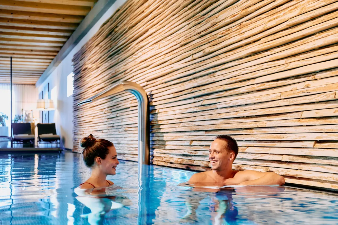 G’Schlössl Murtal in Großlobming – Glückliches Paar entspannt im stilvollen Innenpool | Wellnesshotel Steiermark