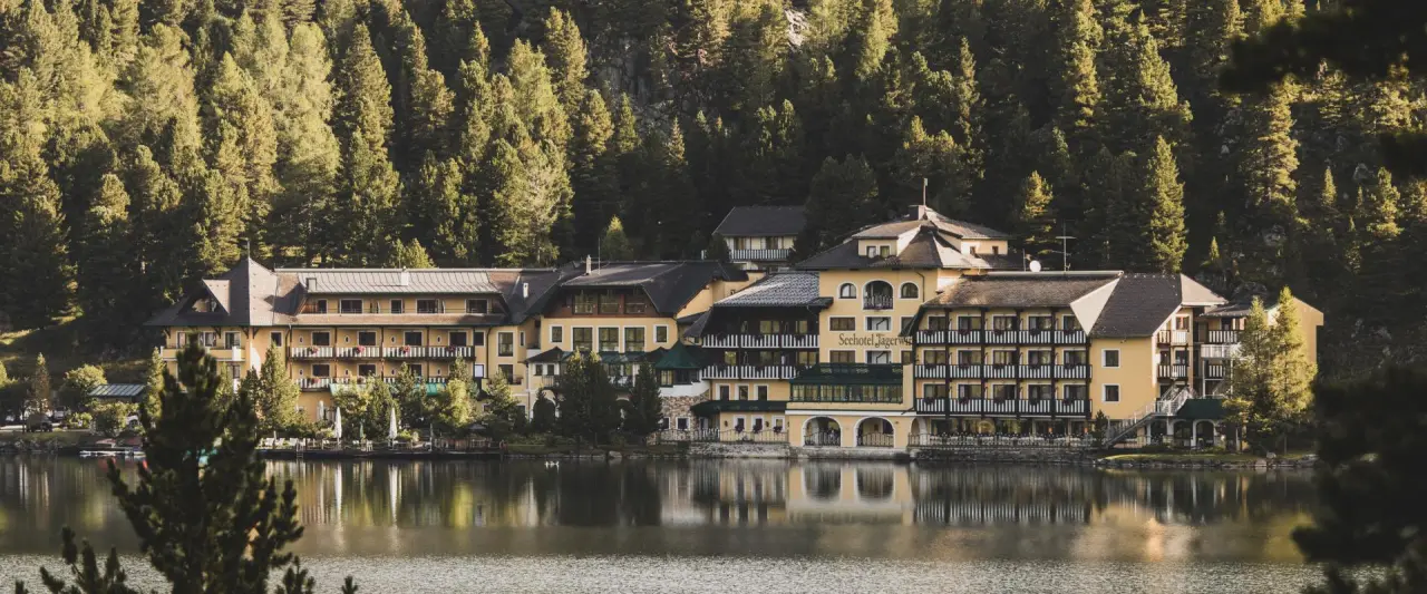 Romantik Seehotel Jägerwirt in Turracher Höhe – Hotelansicht am Seeufer im Sommer | Wellnesshotel Kärnten
