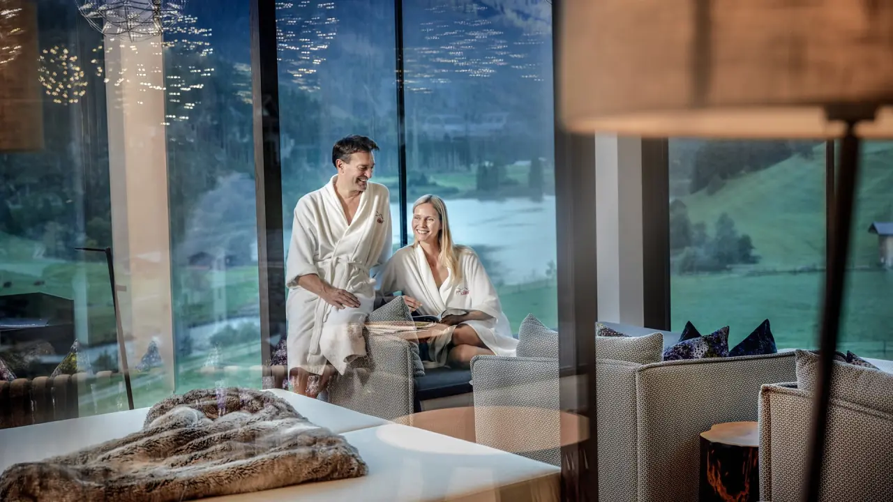 Almhof Family Resort & SPA in Gerlos – Paar in Bademänteln entspannt in Panorama-Lounge | Wellnesshotel Zillertal
