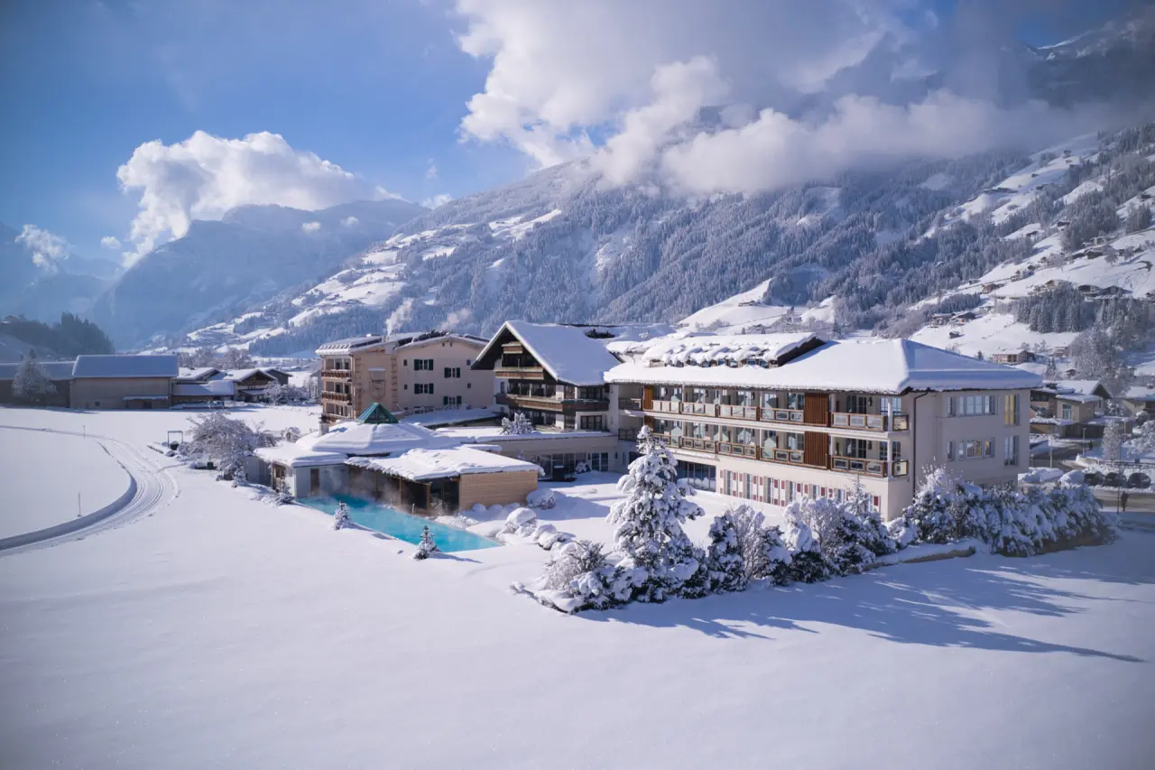 Genießer-Hotel Theresa in Zell am Ziller – Winteransicht des Hotels mit verschneiten Bergen | Wellnesshotel Zillertal