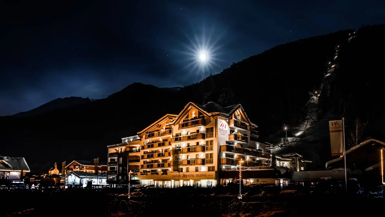 Hotel Mallaun in See/Paznaun – Beleuchtete Hotelfassade bei Nacht unter Vollmond | Wellnesshotel Paznaun