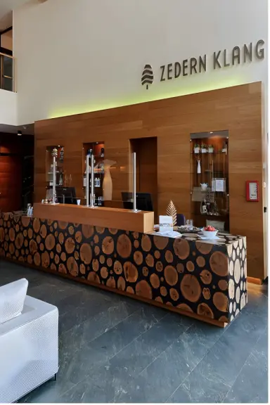 Hotel Zedern Klang in Hopfgarten – Empfangsbereich mit Holztheke und Hotel-Logo | Wellnesshotel Tirol