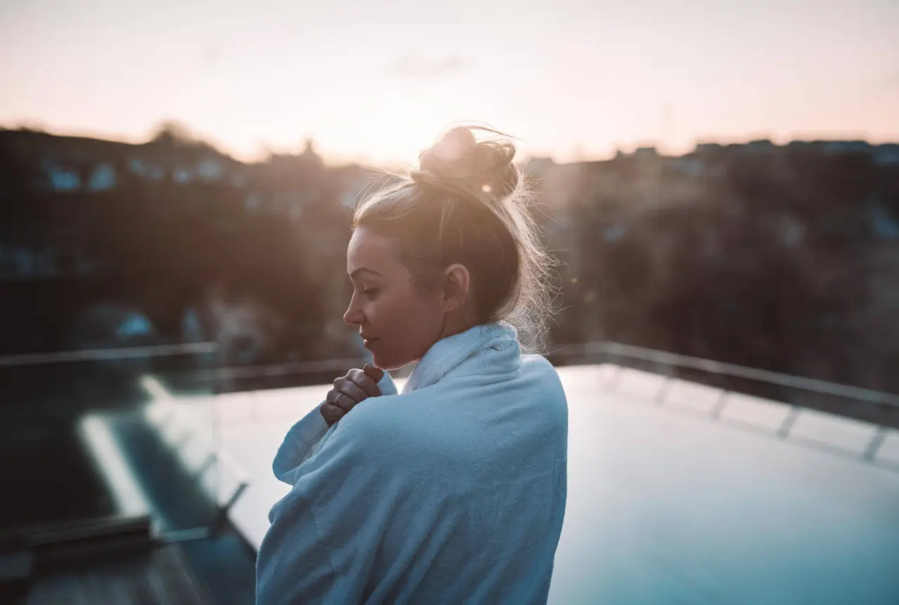 DIEDRICH Wellnesshotel & SPA in Hallenberg – Entspannte Gastin im Bademantel am Außenpool bei Sonnenuntergang | Wellnesshotel Sauerland