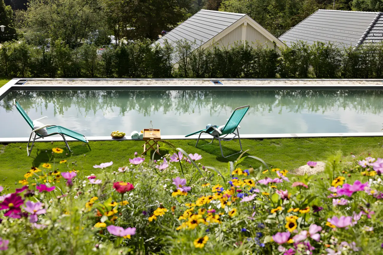 Golfresort Haugschlag in Haugschlag – Idyllischer Außenpool umgeben von blühenden Blumen | Wellnesshotel Waldviertel