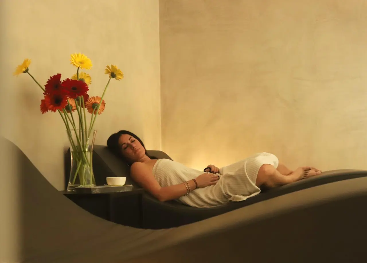 Ca 'Barbini Resort in Garda – Frau entspannt auf einer Liege im Wellnessbereich mit Blumen | Wellnesshotel Gardasee