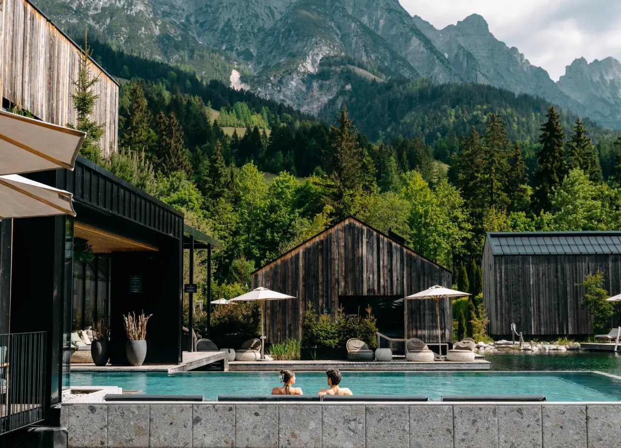 Naturhotel Forsthofgut in Leogang – Paar im Infinity-Pool mit beeindruckendem Bergpanorama | Wellnesshotel Salzburger Land