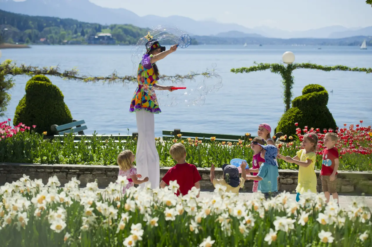 Parkhotel Pörtschach in Pörtschach – Kinder spielen mit Stelzenläufer im Hotelgarten am See | Wellnesshotel Kärnten