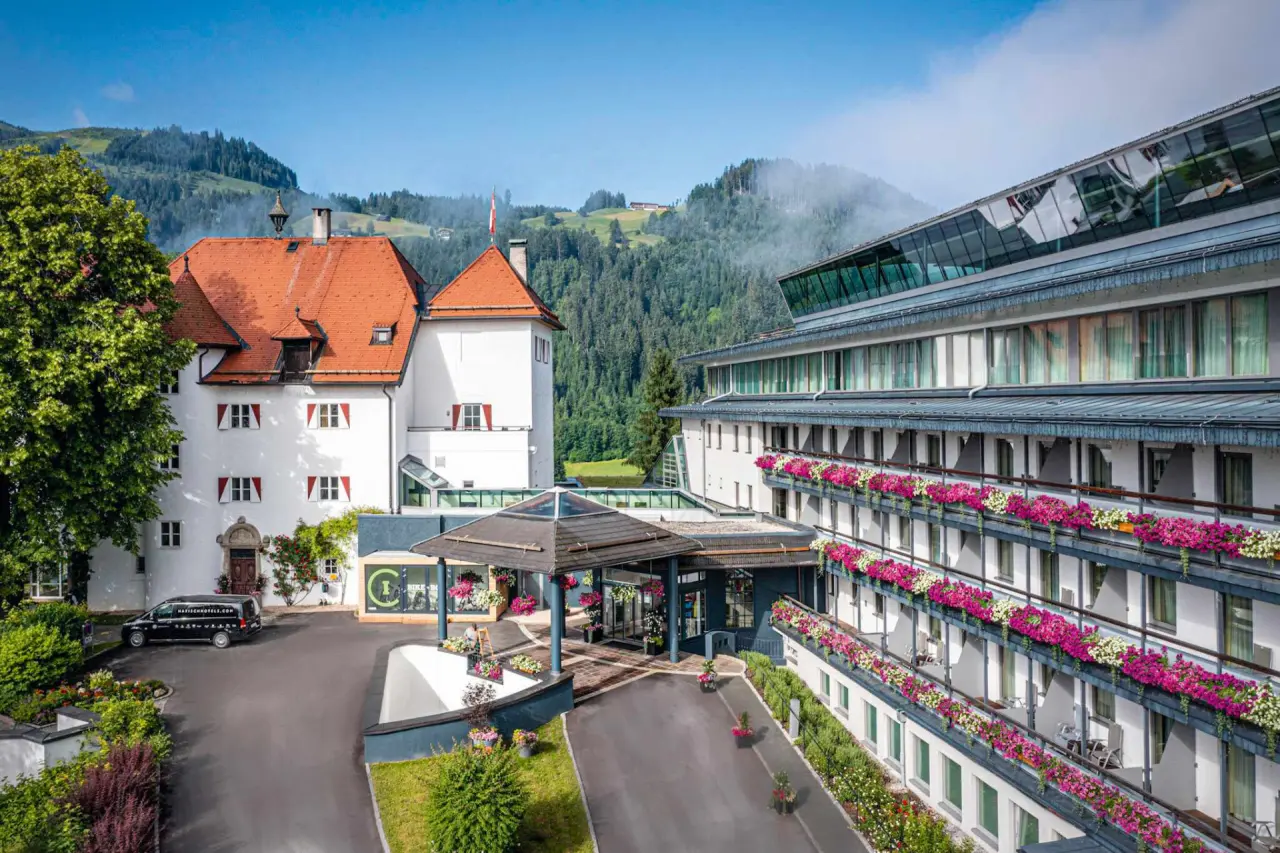 Lebenberger Schlosshotel in Kitzbühel – Hoteleingang mit Blumen und Schlossflügel | Wellnesshotel Tirol
