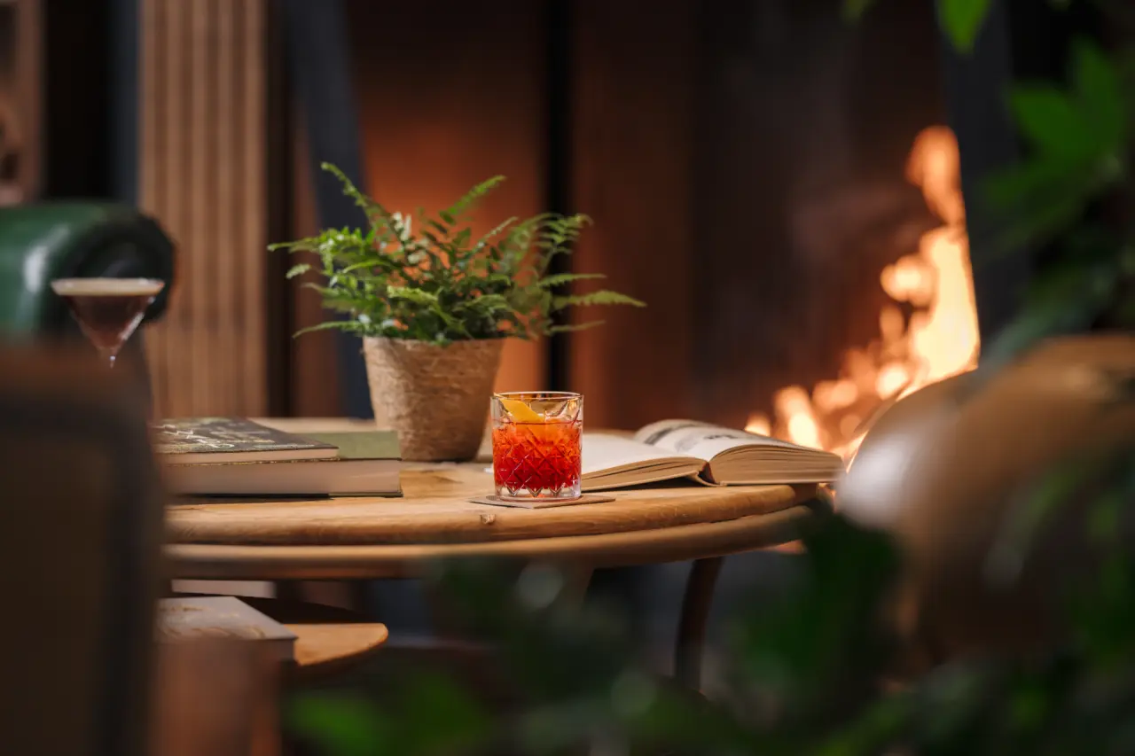 Valsana Hotel Arosa in Arosa – Gemütliche Lounge mit Cocktail und Kaminfeuer | Wellnesshotel Graubünden
