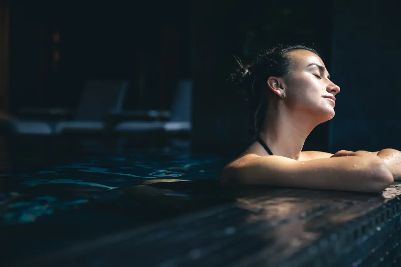 Riverresort Donauschlinge in Haibach/Donau – Frau entspannt im dunklen Poolbereich | Wellnesshotel Oberösterreich