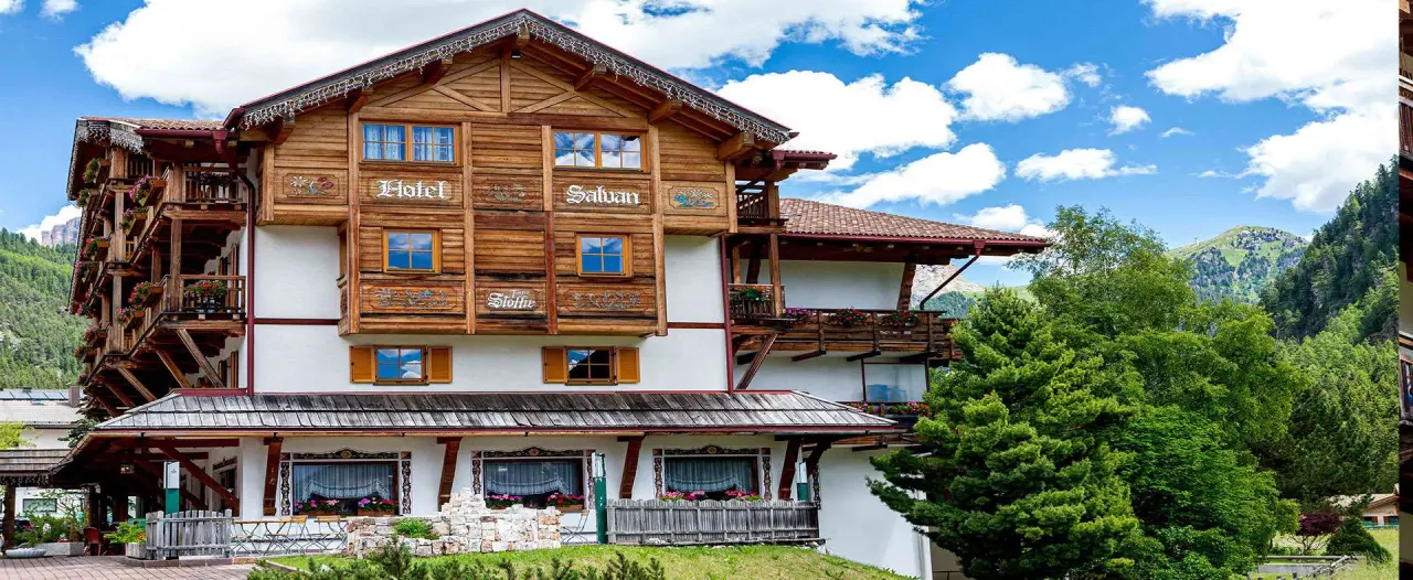 Hotel Salvan in Campitello di Fassa – Gesamtaußenansicht des Hotels mit Berglandschaft | Wellnesshotel Dolomiten