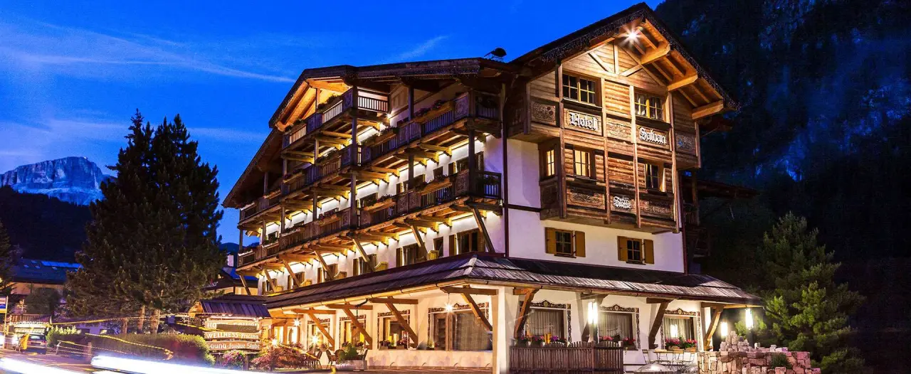 Hotel Salvan in Campitello di Fassa – Beleuchtete Hotelfassade bei Nacht mit Bergkulisse | Wellnesshotel Dolomiten