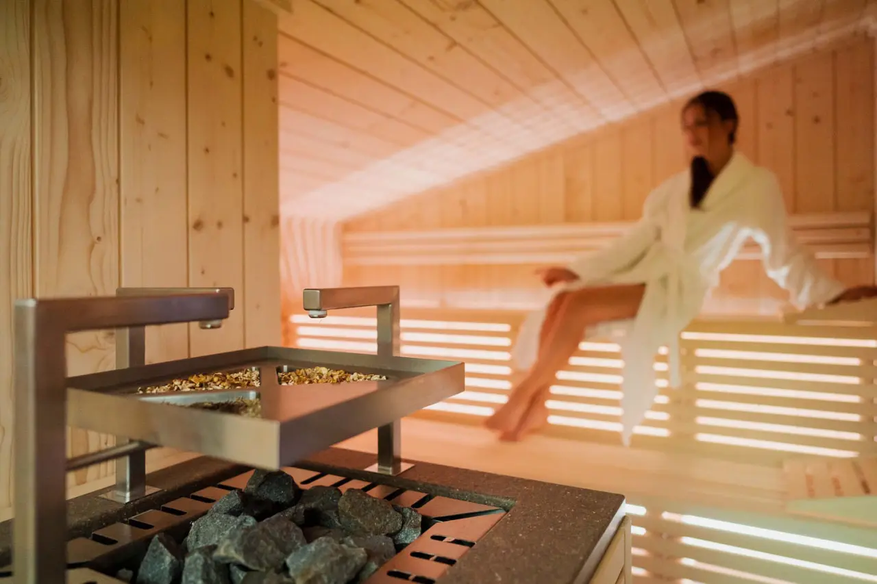 Camina Suite & Spa in Cortina d'Ampezzo – Moderner Saunaofen mit entspannter Person | Wellnesshotel Dolomiten