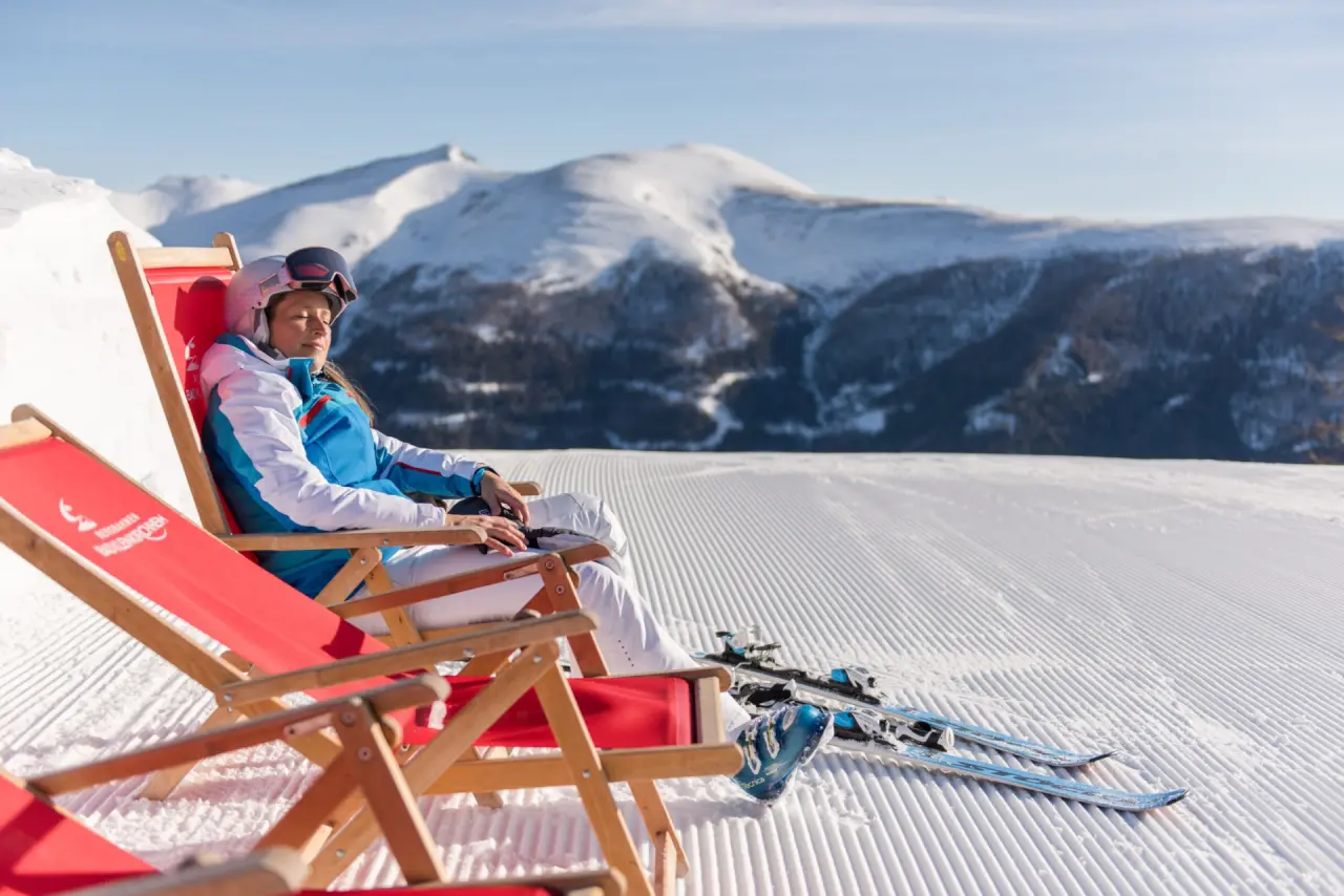 Hotel GUT Trattlerhof & Chalets**** in Bad Kleinkirchheim – Frau entspannt im Liegestuhl im Schnee | Wellnesshotel Kärnten